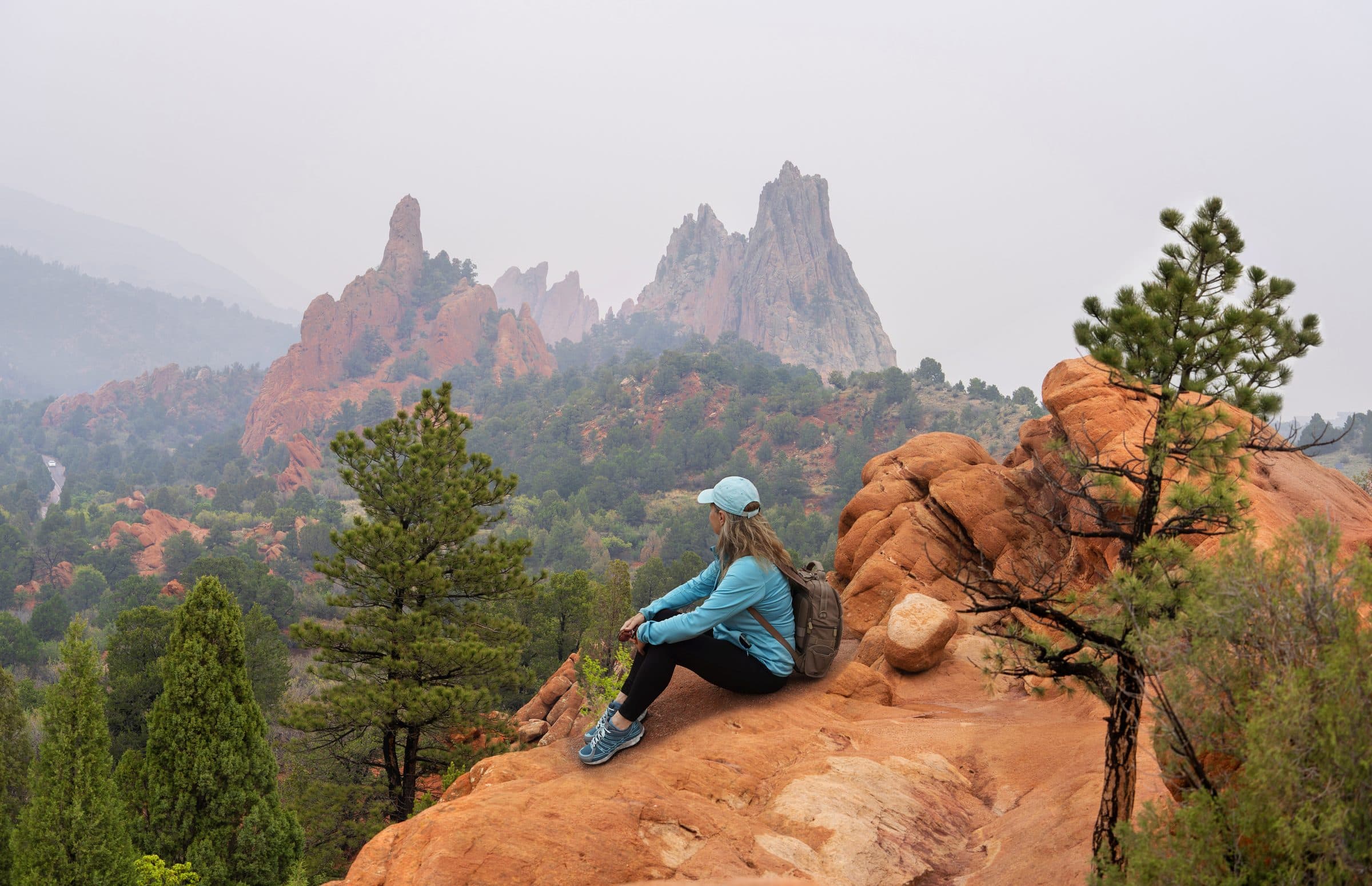 Hiker sitting on red rock below the Garden of the Gods spires
