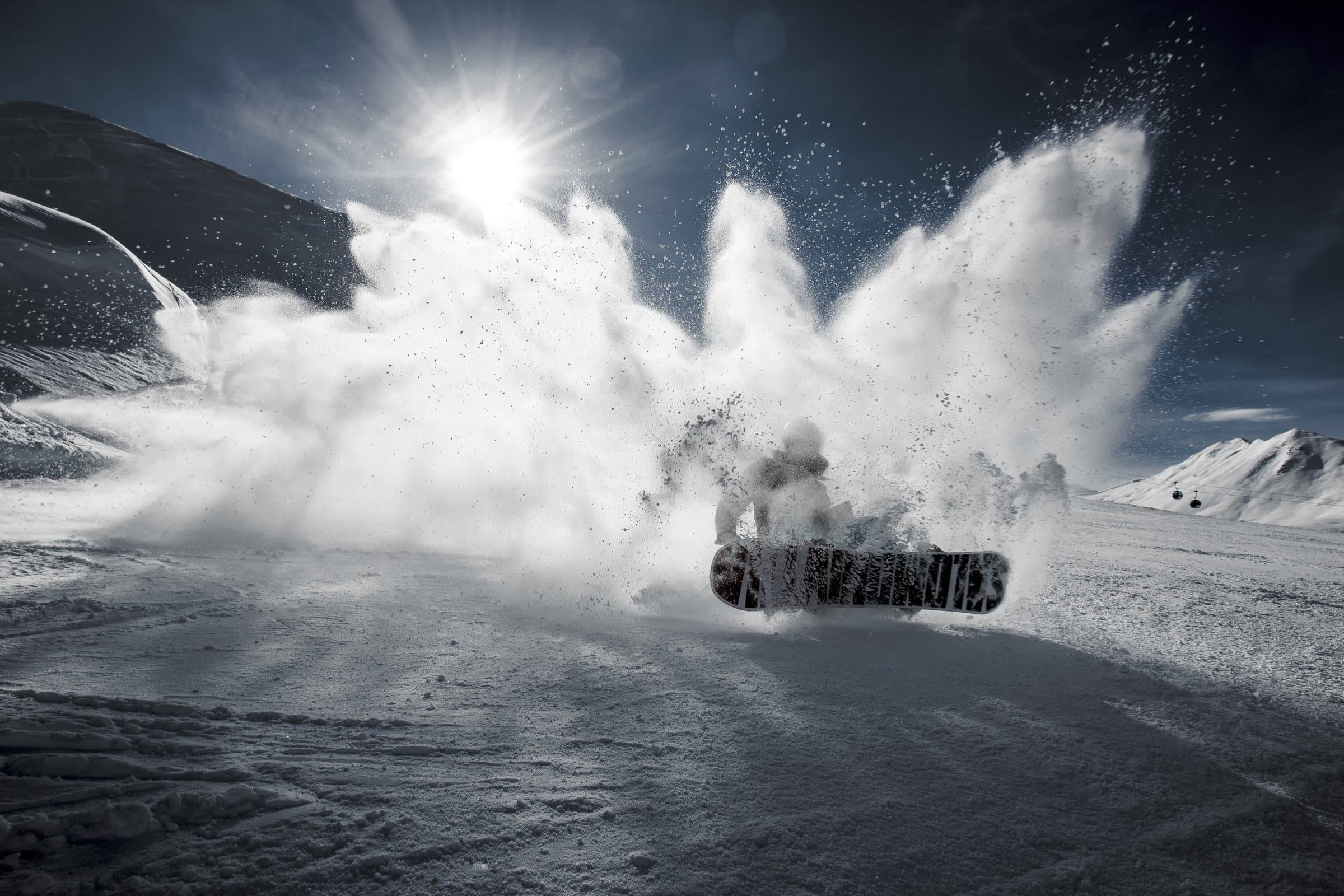A snowboarder spraying powder snow with the board in the air
