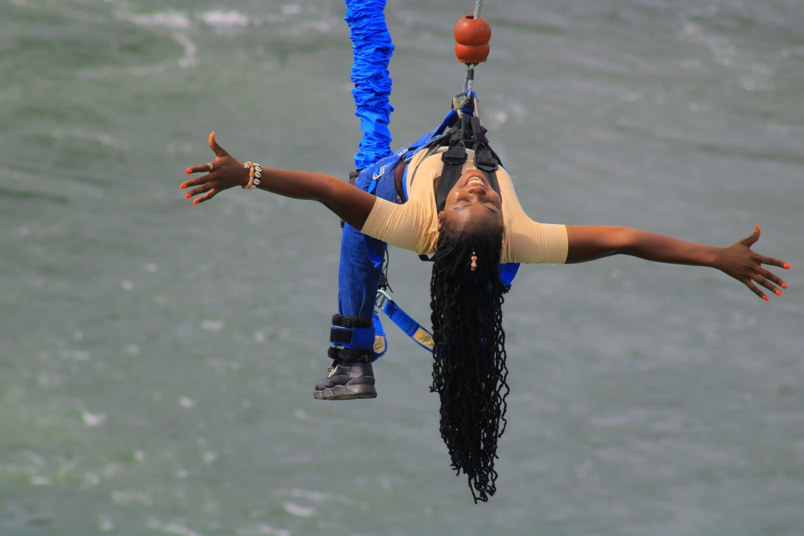 A bungee jumper hanging upside down with arms spread wide