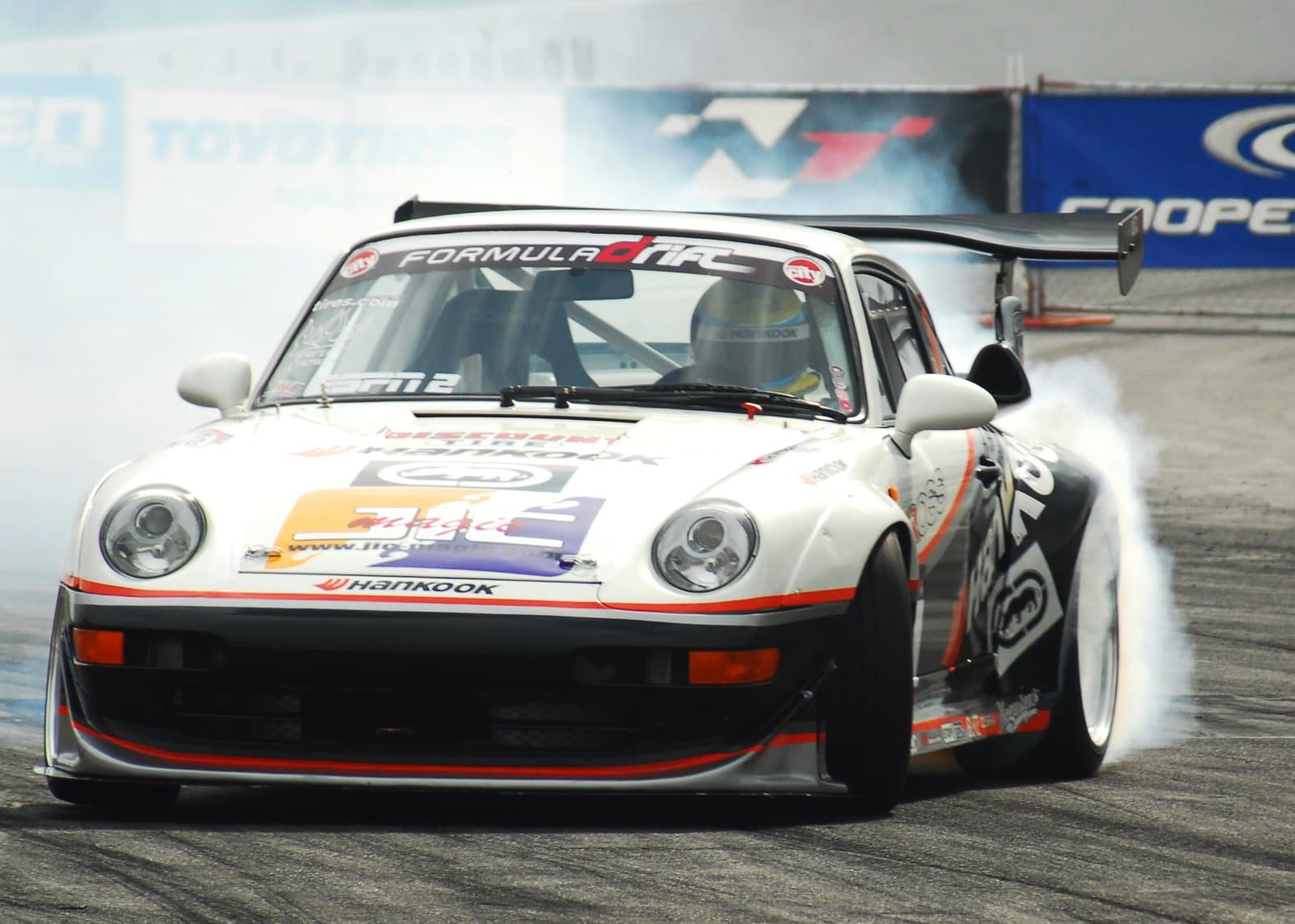 A sports car drifting sideways through a corner with tire smoke