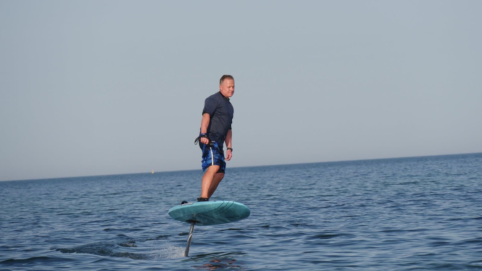A rider standing on an electric hydrofoil board gliding above the water