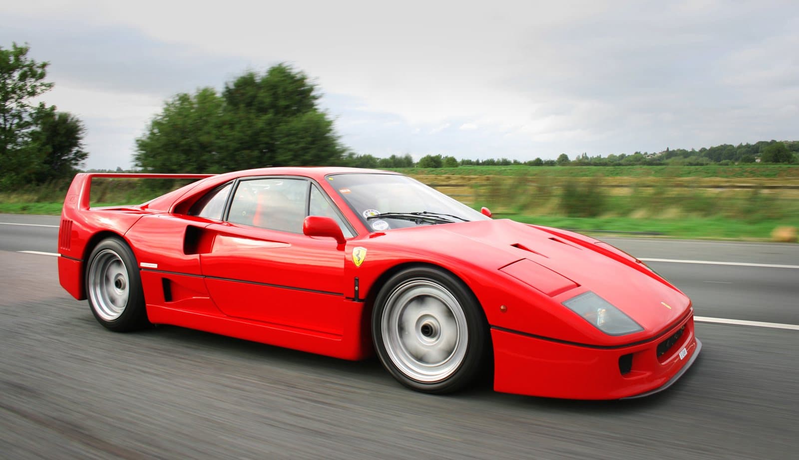 A red exotic sports car driving fast on a country road