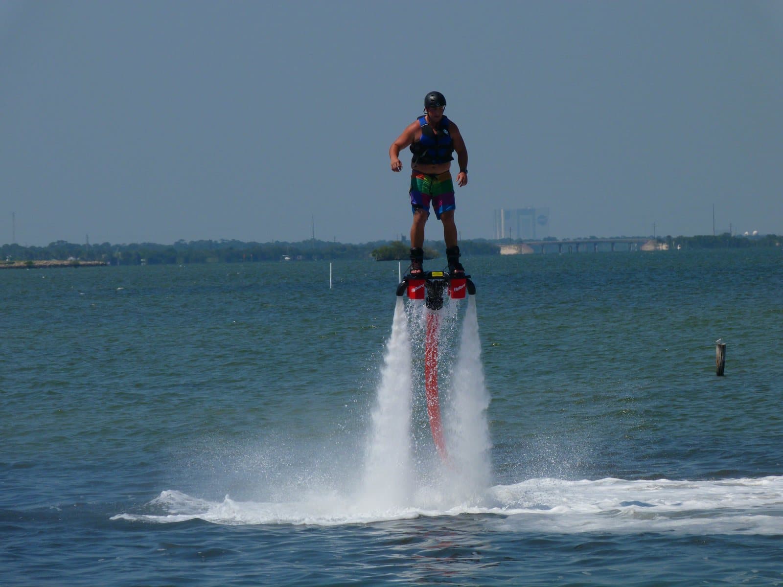 A rider standing on a flyboard, lifted above the water by jets of spray
