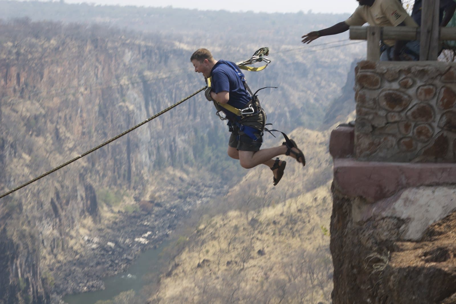 A harnessed jumper swinging out over a deep gorge