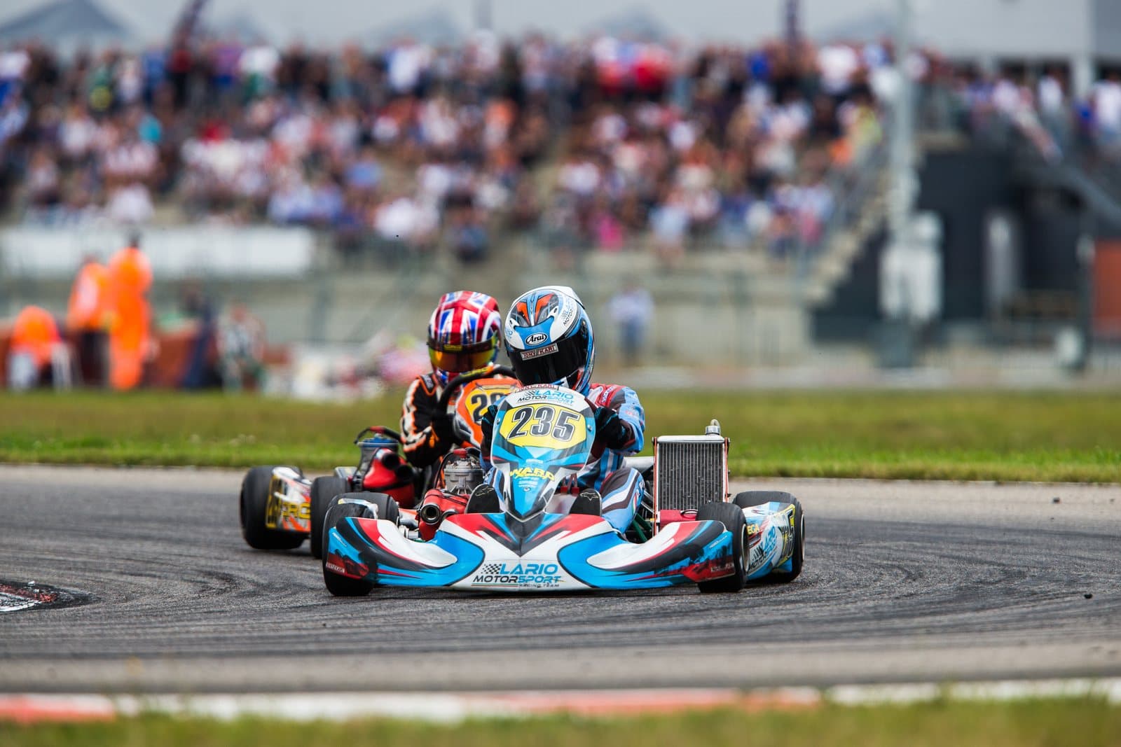 Two racing go-karts leaning through a corner on an outdoor kart circuit