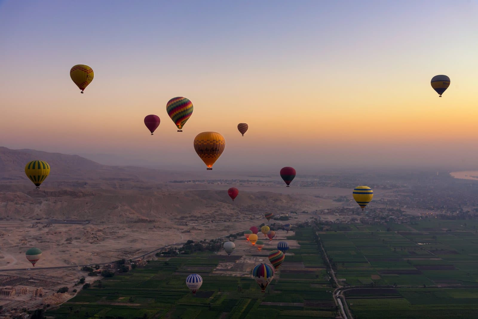 Hot air balloons flying at sunrise over the Nile valley near the Valley of the Kings
