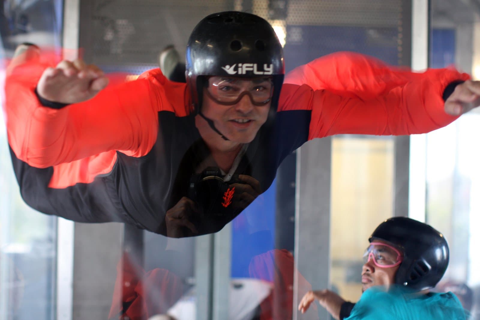 A person bodyflying with arms spread inside a vertical wind tunnel