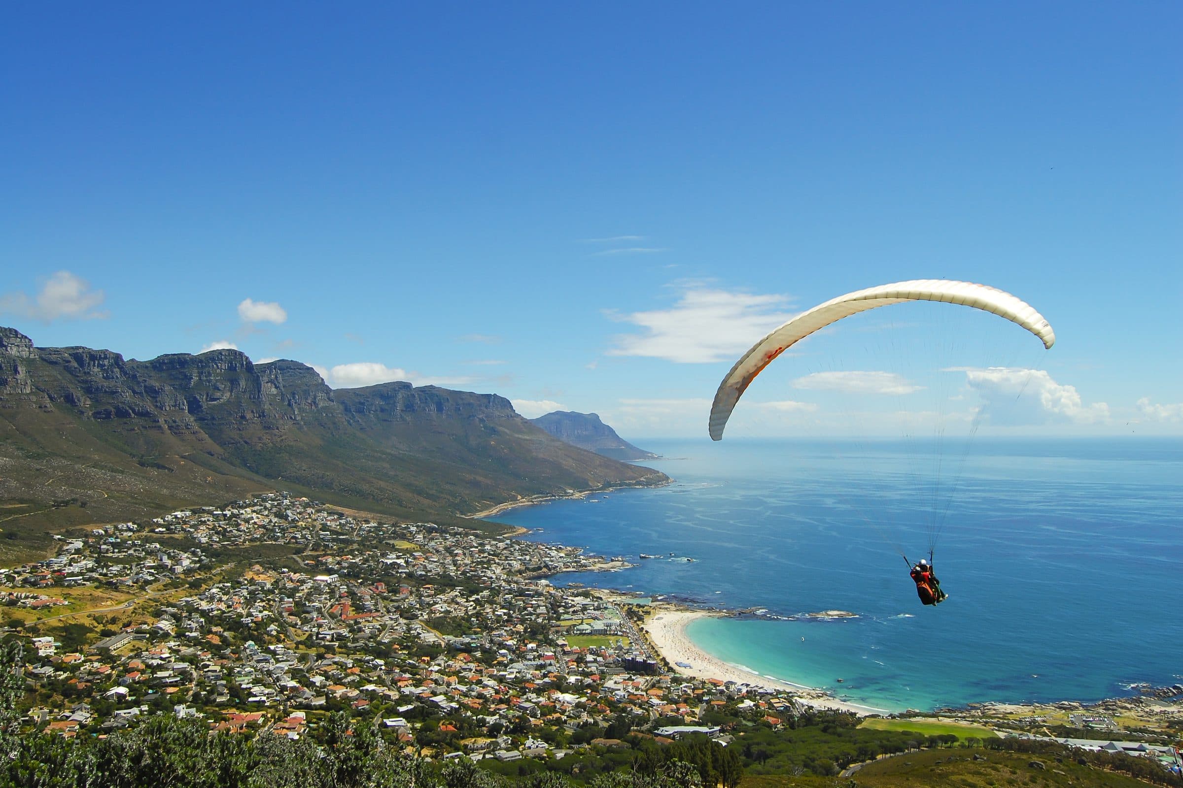 Paraglider over a bright coastline and bay