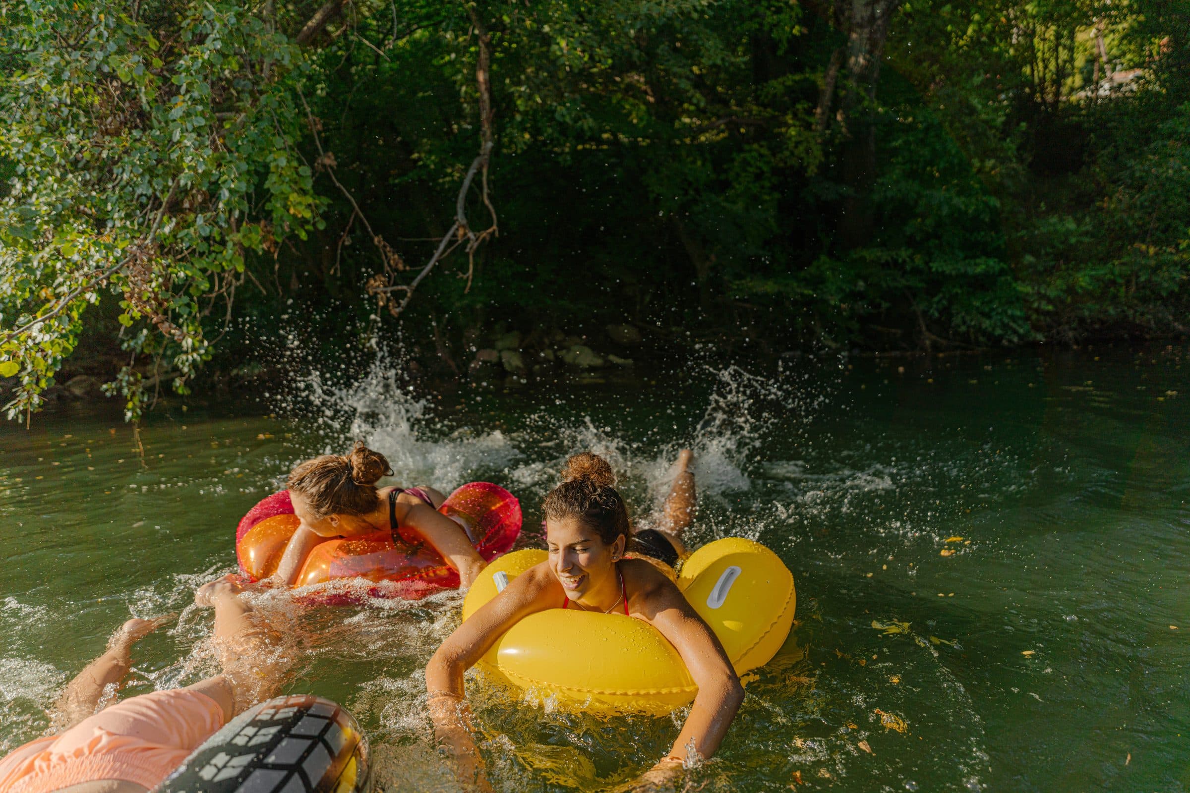 Friends on colorful tubes splashing down a lively river