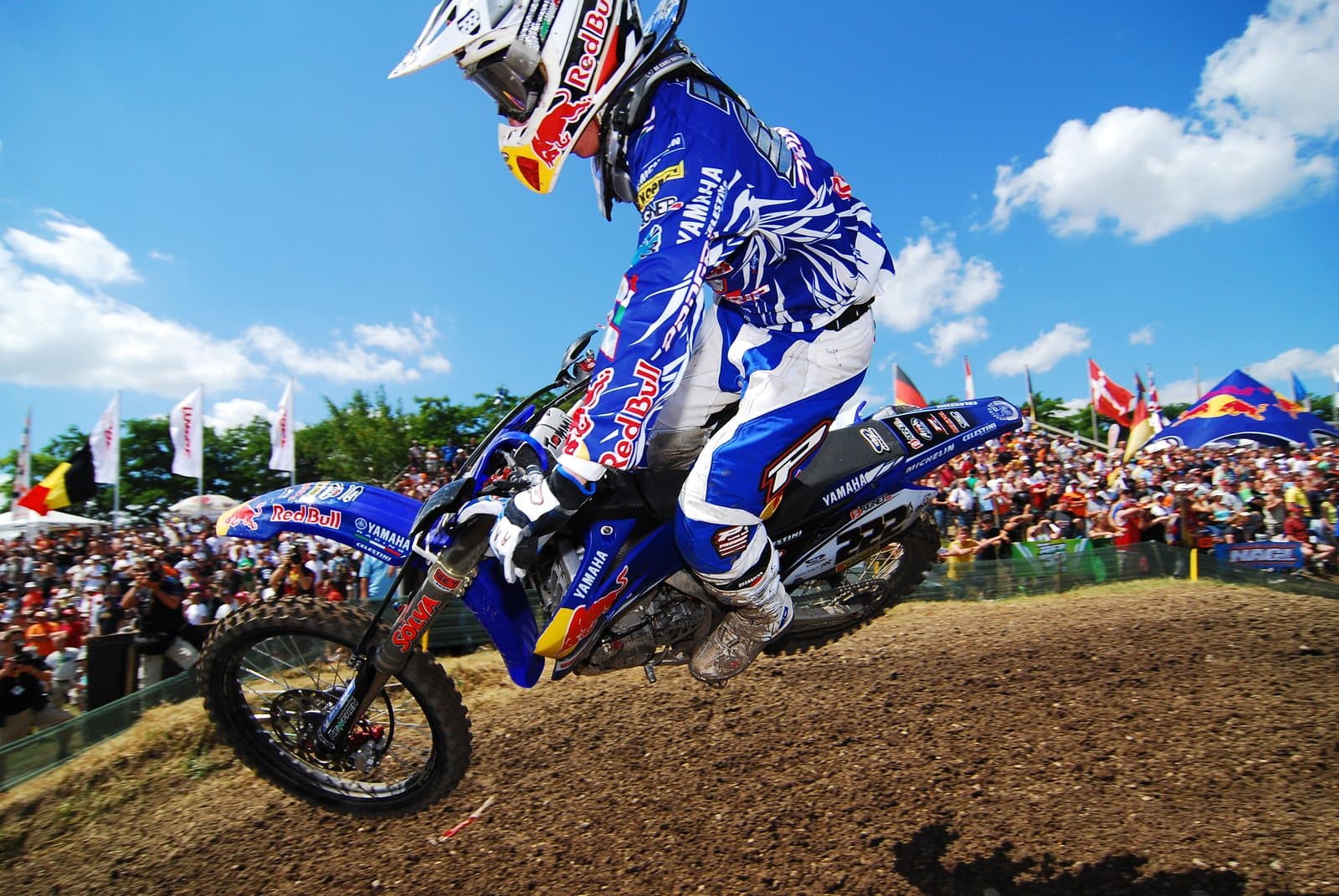 A motocross rider airborne over a jump in front of a crowd