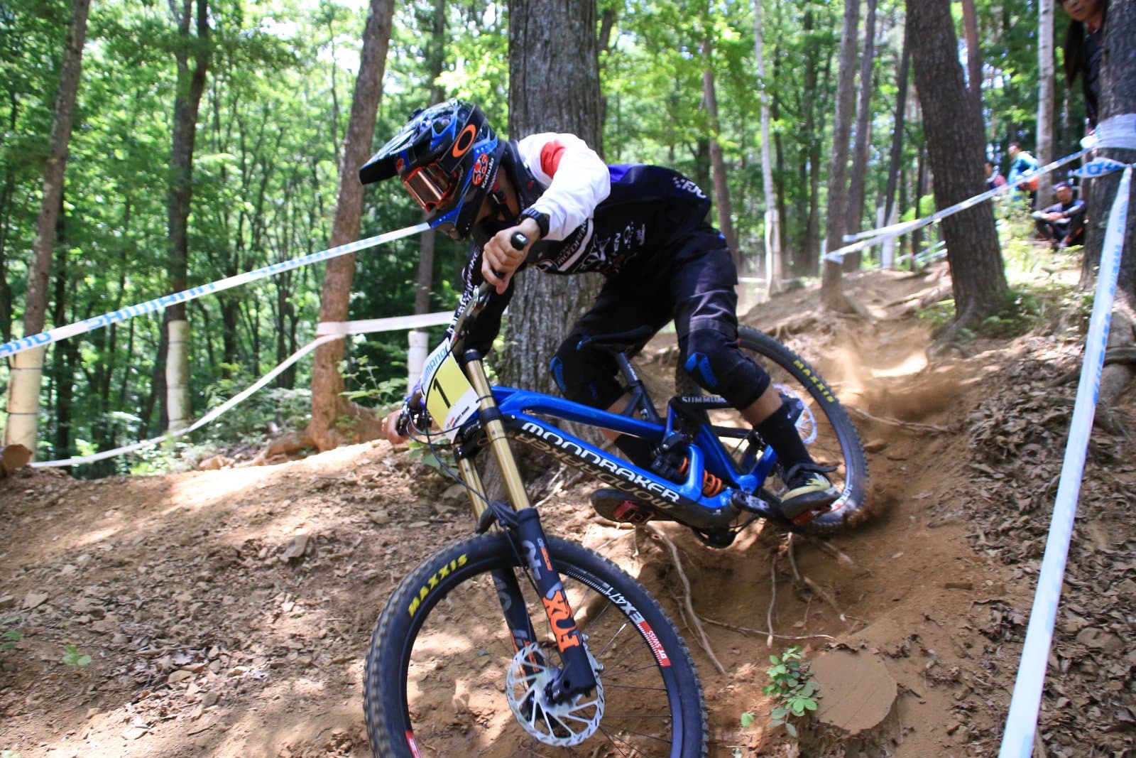 A downhill mountain biker leaning into a dirt turn in the forest