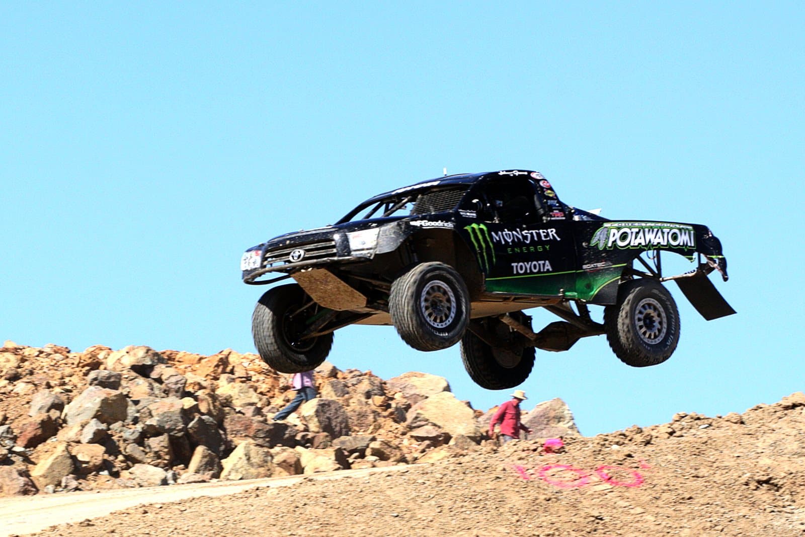 An off-road race truck airborne over a dirt jump