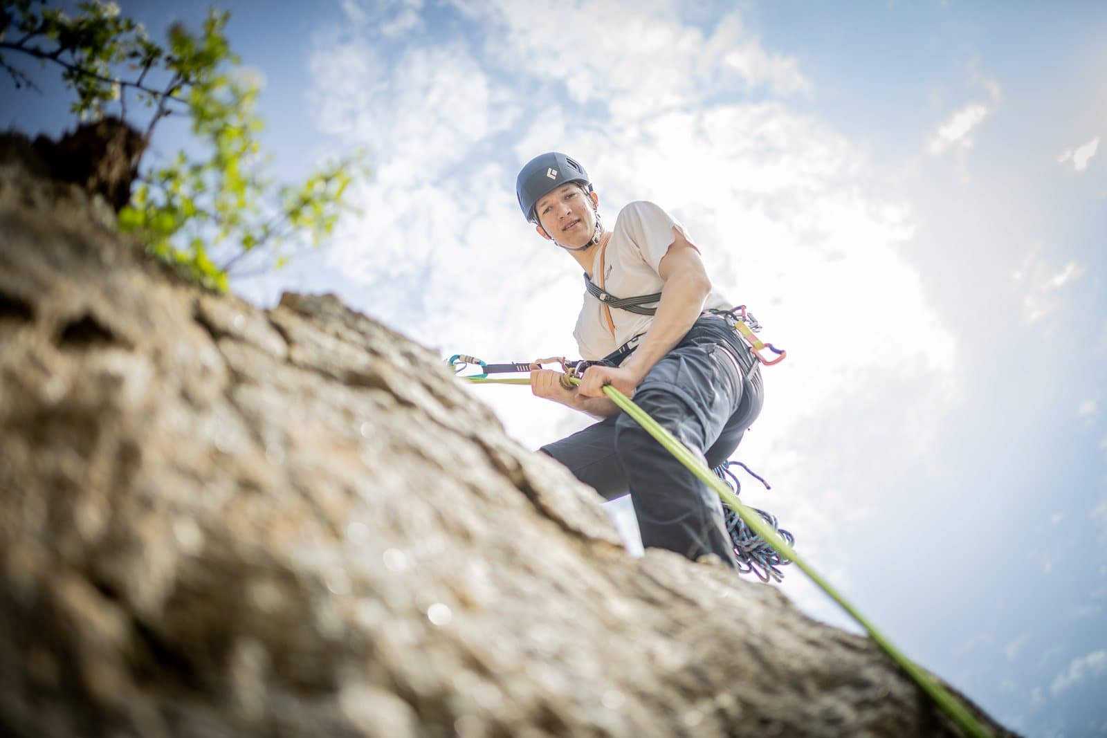 A climber in a helmet rappelling down a rock face