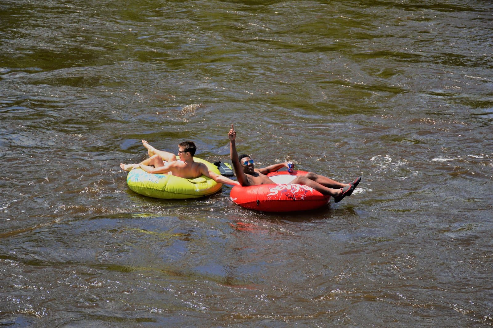 Two people floating down a river on inflatable tubes