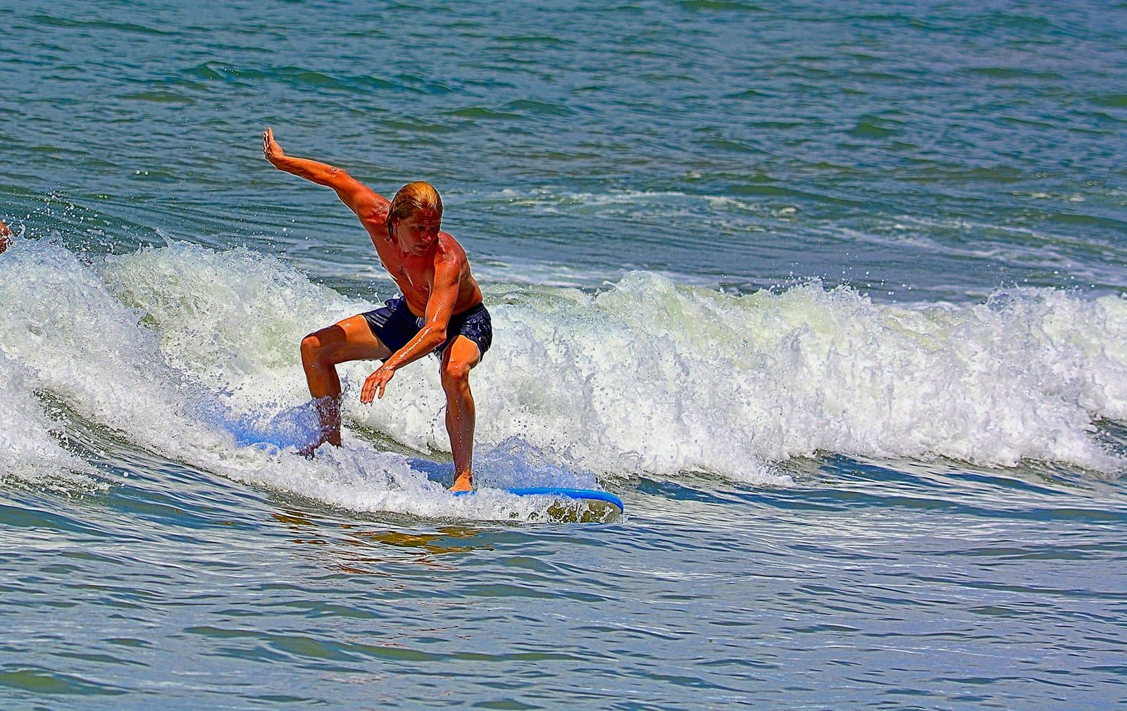 A surfer riding a breaking wave with arms out for balance