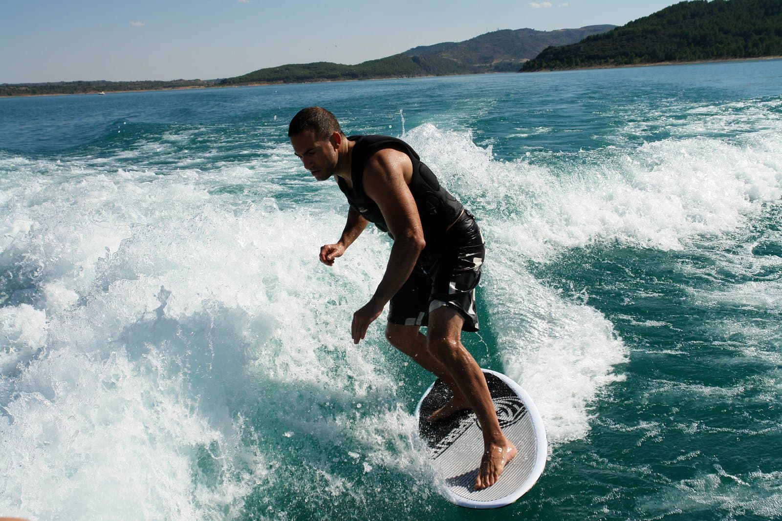 A wakesurfer riding a boat wake without a rope