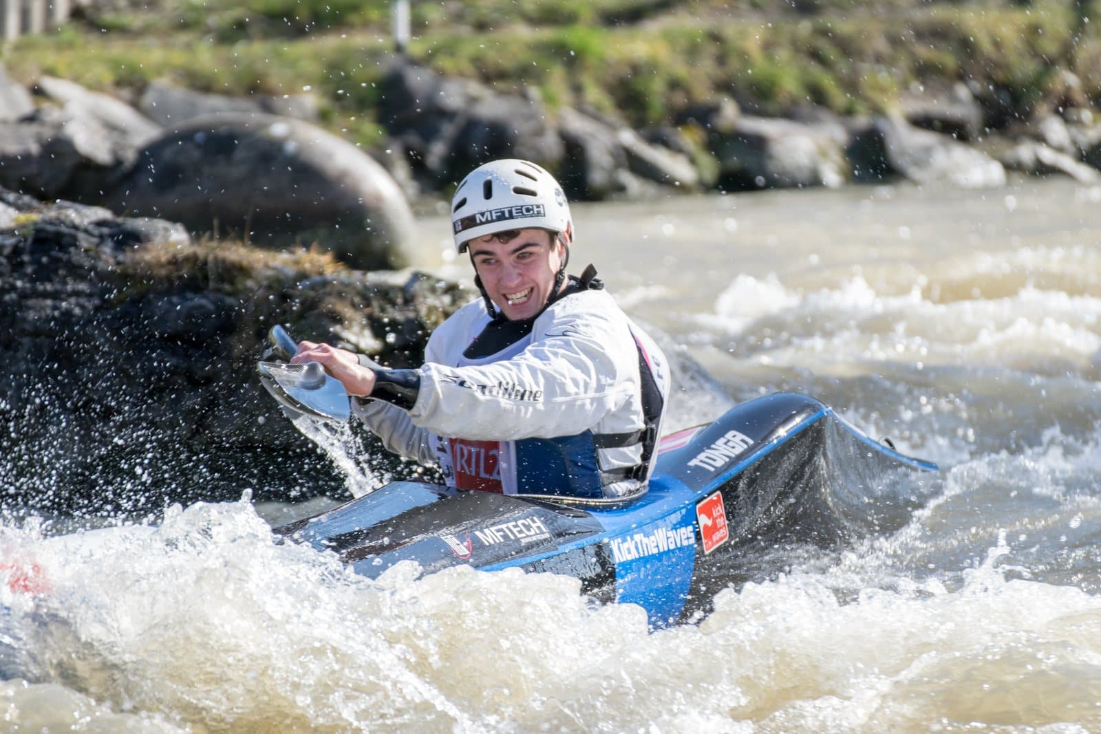 A kayaker in a helmet paddling through river whitewater