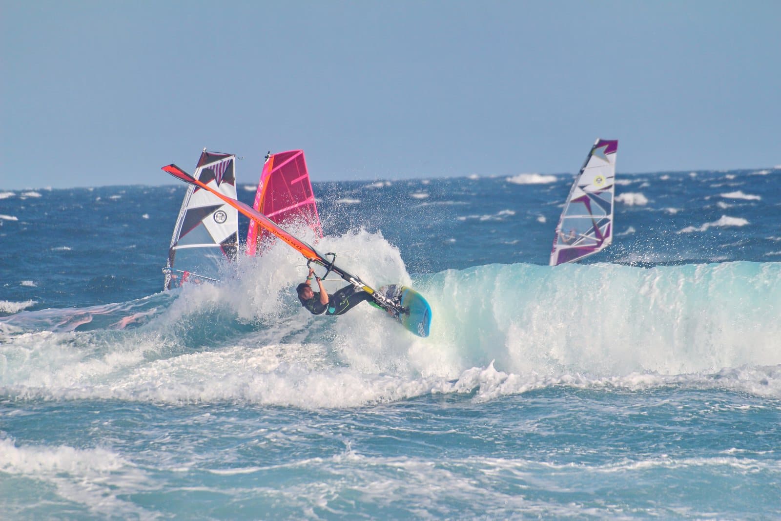 Windsurfers riding waves with colorful sails
